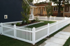 White vinyl picket fence surrounding landscaped yard, showcasing durability and aesthetic appeal, emphasizing low maintenance and weather resistance features.